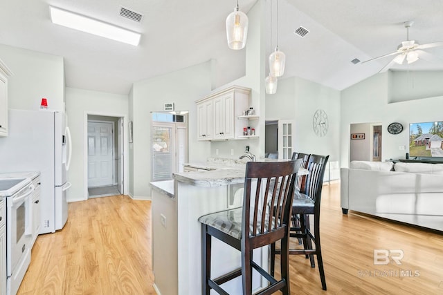 kitchen with white electric range, light hardwood / wood-style floors, decorative light fixtures, a kitchen bar, and white cabinets