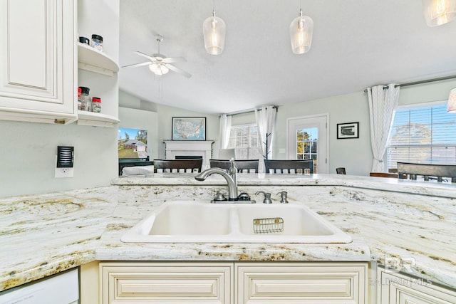 kitchen with white dishwasher, vaulted ceiling, ceiling fan, sink, and decorative light fixtures