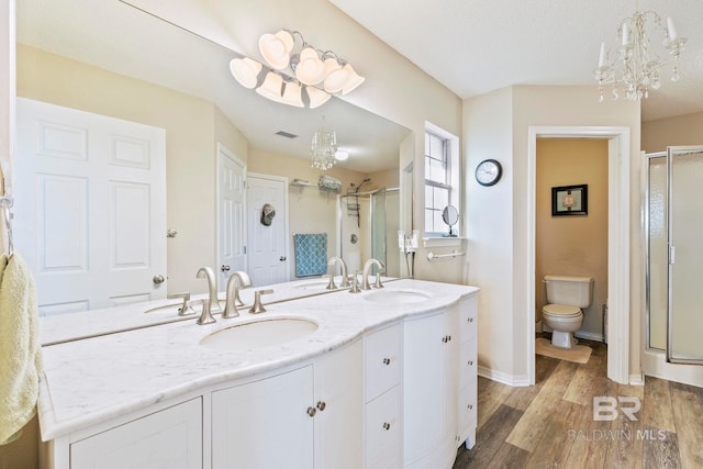 bathroom featuring hardwood / wood-style floors, vanity, toilet, walk in shower, and a notable chandelier