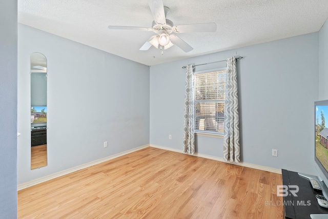 spare room featuring ceiling fan, light hardwood / wood-style flooring, and a textured ceiling