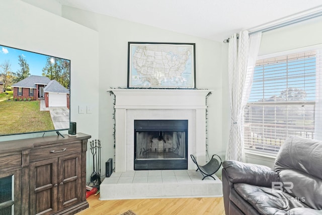 living room with a tile fireplace, light hardwood / wood-style floors, and lofted ceiling