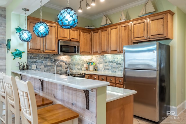 630 Lemoyne Dr Unit 8D, Dauphin Island, AL 36528 - kitchen with brown cabinetry, a peninsula, appliances with stainless steel finishes, and backsplash