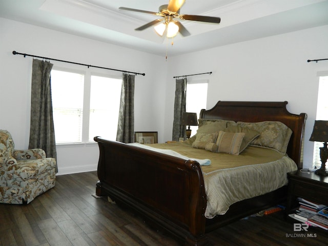 bedroom with dark hardwood / wood-style floors, ceiling fan, a raised ceiling, and ornamental molding