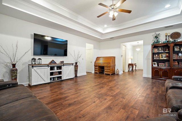 living room with dark hardwood / wood-style flooring, a tray ceiling, ceiling fan, and ornamental molding