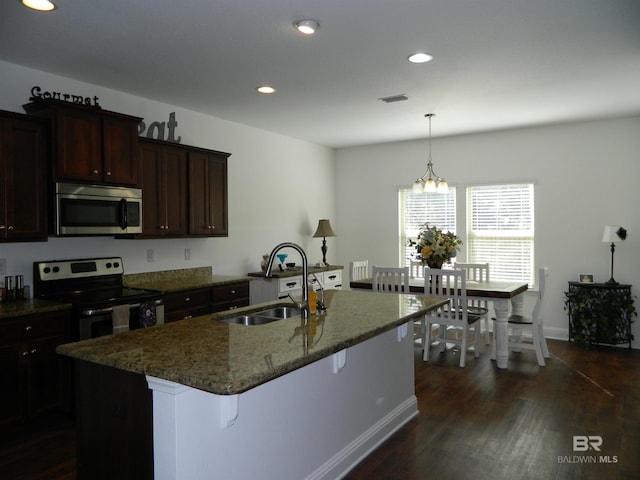 kitchen featuring a kitchen bar, stainless steel appliances, a kitchen island with sink, dark wood-type flooring, and sink