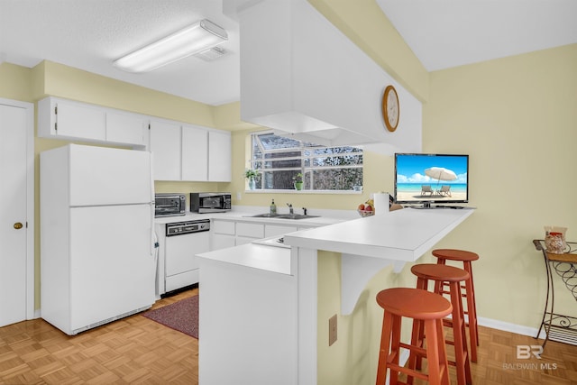 2277 Oyster Bay Ln Unit 502, Gulf Shores, AL 36542 - kitchen with a sink, a kitchen breakfast bar, white appliances, a peninsula, and white cabinetry