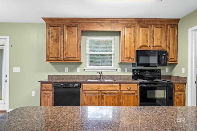 kitchen featuring sink, dark stone counters, and black appliances