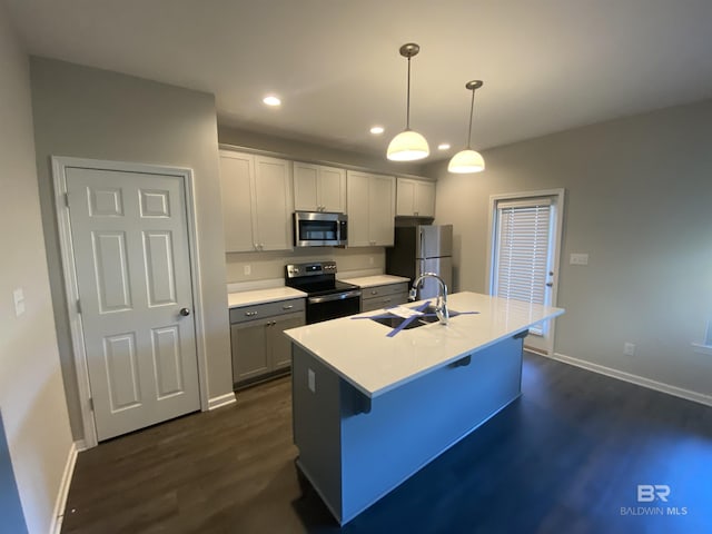 kitchen with a center island with sink, sink, hanging light fixtures, a kitchen bar, and stainless steel appliances