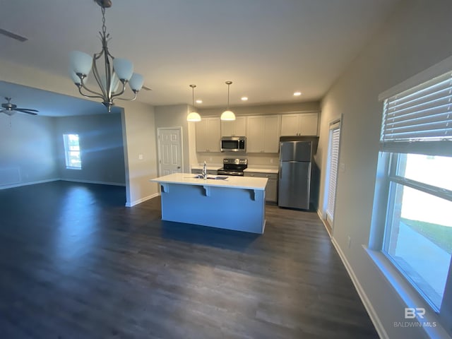 kitchen featuring appliances with stainless steel finishes, a kitchen island with sink, sink, pendant lighting, and white cabinetry