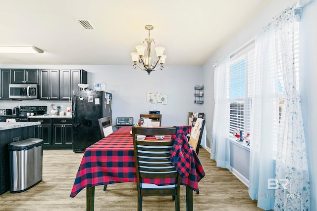 dining room with light hardwood / wood-style flooring and a notable chandelier