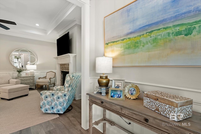 sitting room with hardwood / wood-style flooring, ceiling fan, a tray ceiling, a fireplace, and ornamental molding