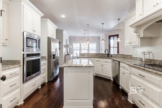 kitchen featuring kitchen peninsula, stainless steel appliances, a kitchen island, decorative light fixtures, and white cabinetry