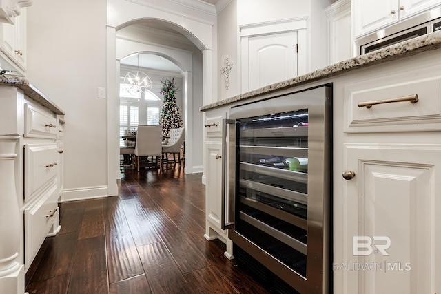 bar with wine cooler, light stone countertops, white cabinets, and dark hardwood / wood-style floors