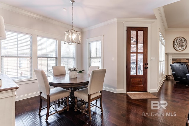 dining area with a notable chandelier, dark hardwood / wood-style flooring, ornamental molding, and a fireplace