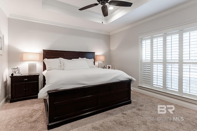 carpeted bedroom with a raised ceiling, ceiling fan, and ornamental molding