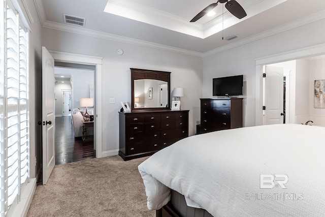 bedroom with light carpet, a tray ceiling, ceiling fan, and crown molding