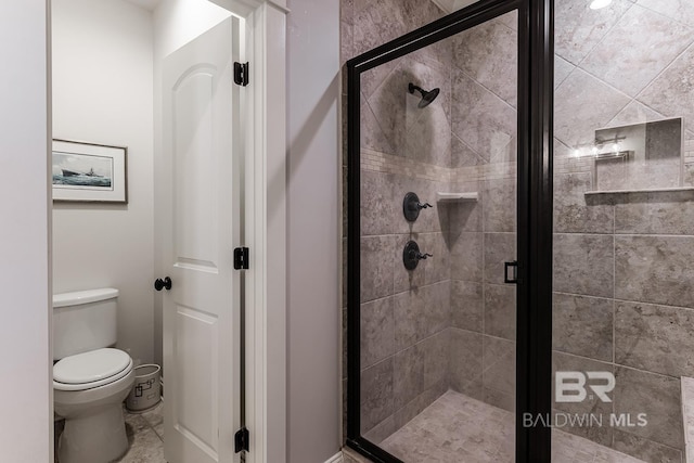 bathroom featuring toilet and a shower with door