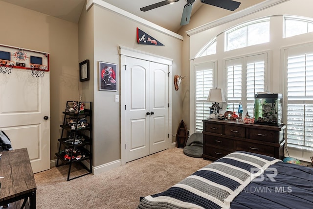 bedroom featuring ceiling fan, a closet, light colored carpet, and lofted ceiling