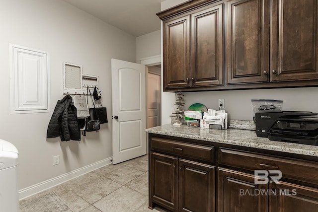 kitchen featuring light stone countertops, light tile patterned floors, and dark brown cabinetry