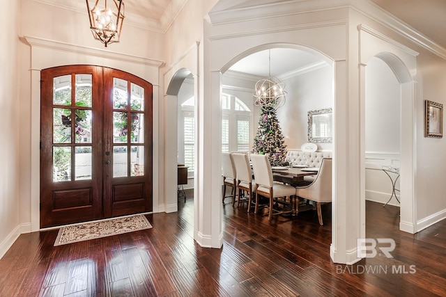 foyer entrance with dark hardwood / wood-style flooring, crown molding, french doors, and a notable chandelier