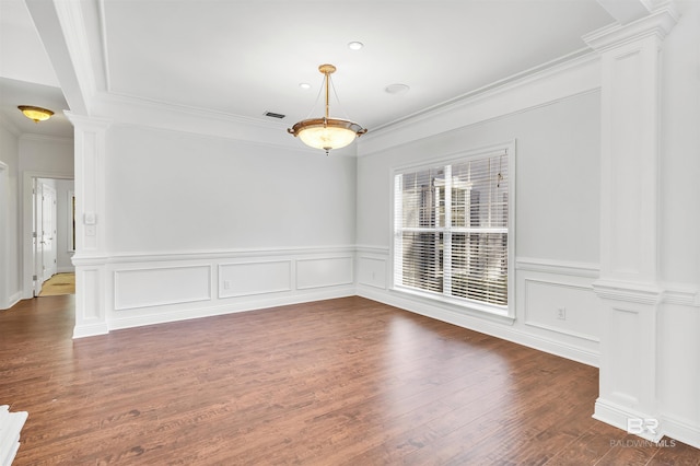 spare room featuring ornamental molding, dark hardwood / wood-style flooring, and ornate columns