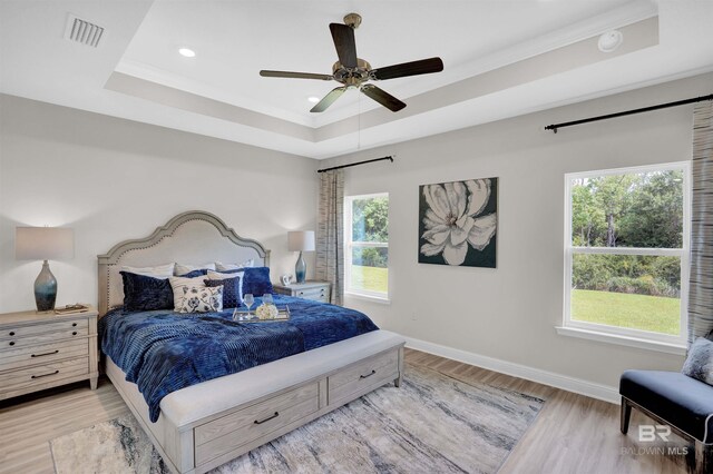 12753 Shoshoney Cir, Fairhope, AL 36532 - bedroom with a ceiling fan, baseboards, visible vents, a tray ceiling, and light wood-style floors