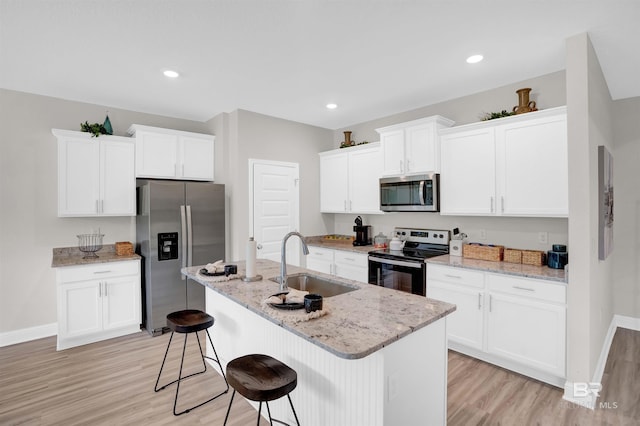12753 Shoshoney Cir, Fairhope, AL 36532 - kitchen featuring a breakfast bar, stainless steel appliances, light wood-style floors, white cabinetry, and a sink