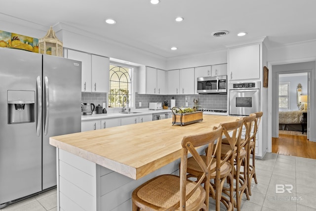 kitchen with stainless steel appliances, tasteful backsplash, sink, and white cabinets