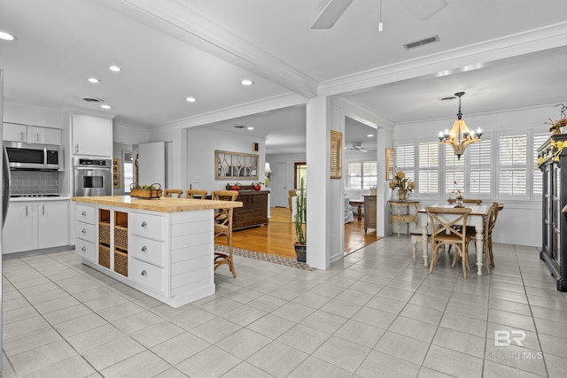 kitchen with a healthy amount of sunlight, light tile patterned floors, stainless steel appliances, and white cabinets