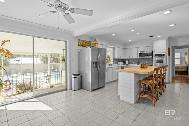 kitchen with sink, white cabinetry, tasteful backsplash, wooden counters, and appliances with stainless steel finishes