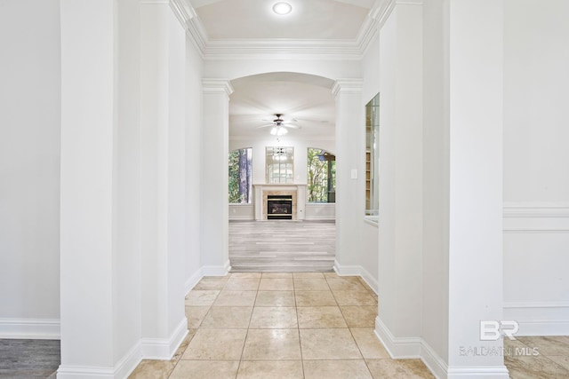 corridor featuring light wood-type flooring, ornate columns, and ornamental molding