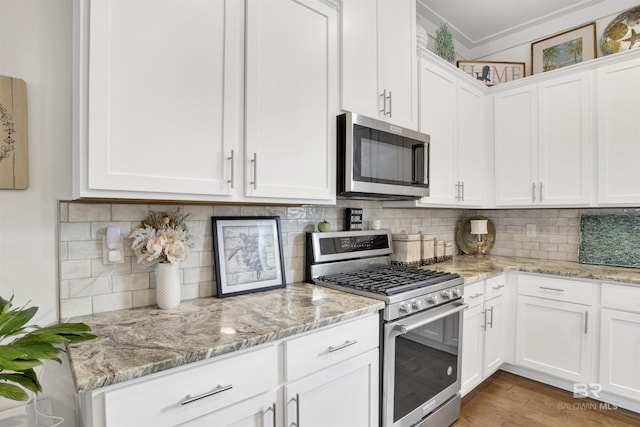 kitchen with stainless steel appliances, white cabinetry, light wood-type flooring, decorative backsplash, and light stone countertops