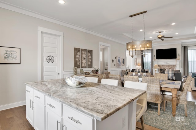 kitchen featuring a kitchen island, white cabinets, open floor plan, decorative light fixtures, and crown molding