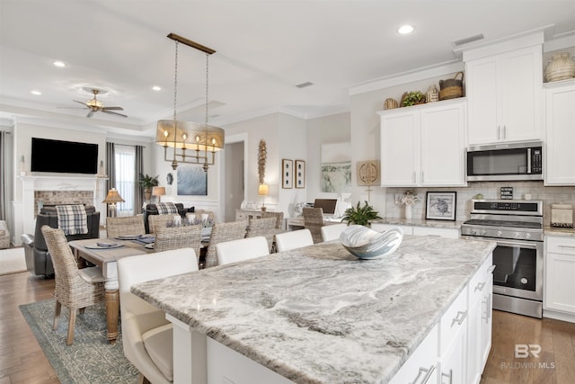 kitchen with open floor plan, stainless steel appliances, a kitchen island, and white cabinetry