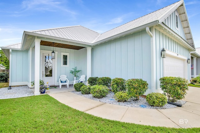 view of front facade with a porch, board and batten siding, a front yard, metal roof, and a garage