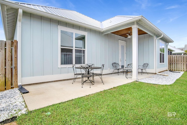 rear view of property with board and batten siding, fence, a patio, and a lawn