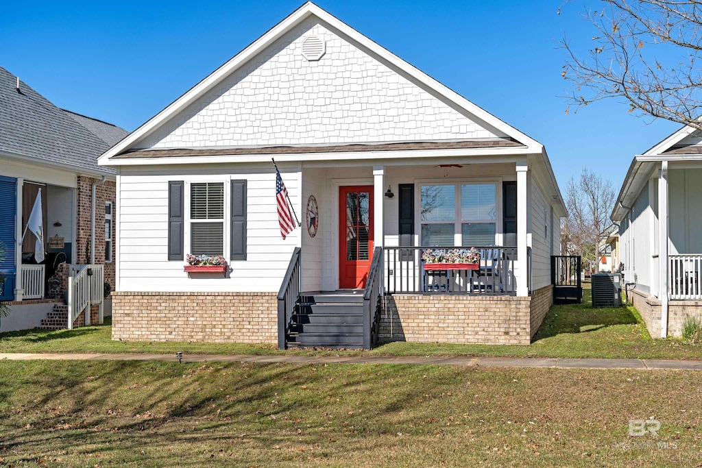 bungalow-style home featuring a front yard, cooling unit, and covered porch