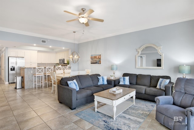 tiled living room with ceiling fan with notable chandelier and crown molding