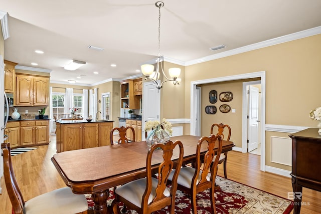 dining room with crown molding, an inviting chandelier, and light wood-type flooring