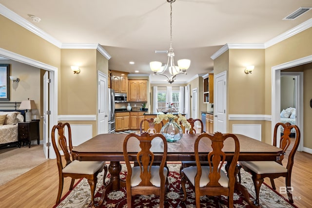 dining room featuring an inviting chandelier, crown molding, and light wood-type flooring