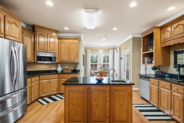 kitchen with crown molding, appliances with stainless steel finishes, sink, and an island with sink