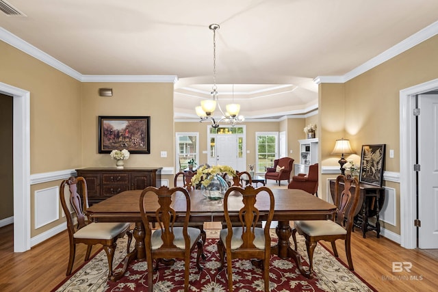 dining room with an inviting chandelier, ornamental molding, and light hardwood / wood-style floors