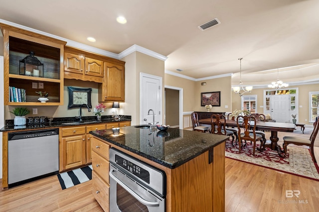 kitchen featuring pendant lighting, sink, appliances with stainless steel finishes, and a center island with sink