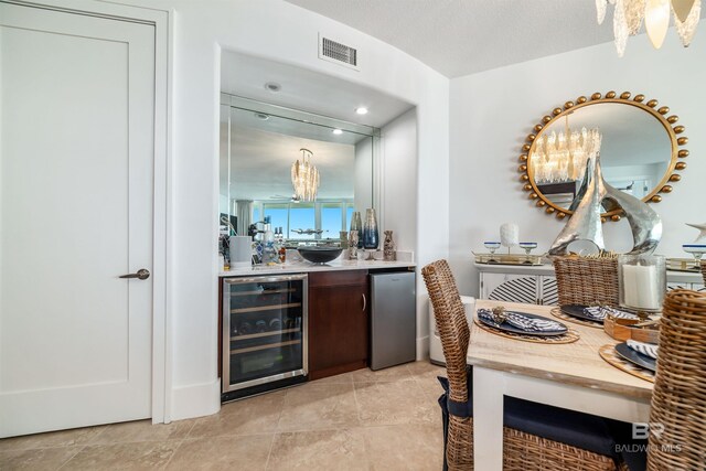 bar featuring refrigerator, visible vents, a chandelier, light tile patterned flooring, and wine cooler
