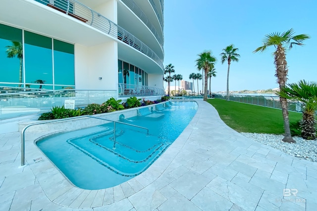 pool with fence, a patio area, and a lawn