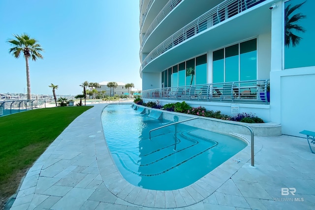 community pool with a patio and a lawn