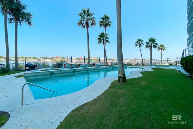 view of swimming pool with fence, a water view, a fenced in pool, and a lawn
