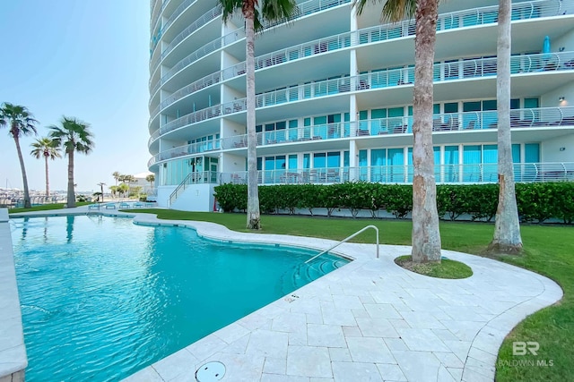 pool featuring a patio and a lawn
