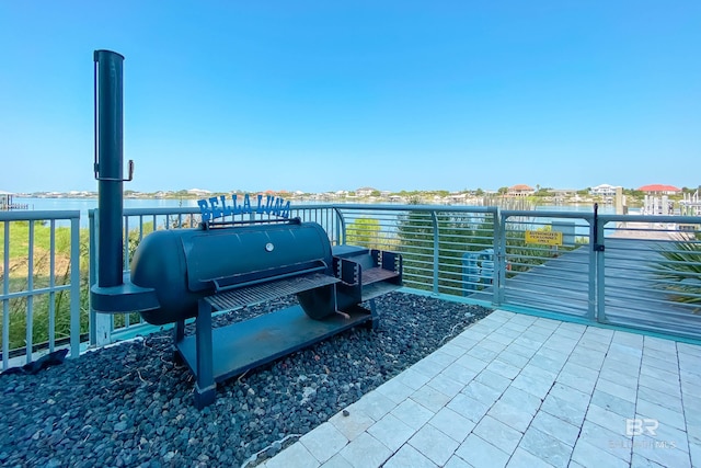 view of patio featuring grilling area, a water view, and a balcony