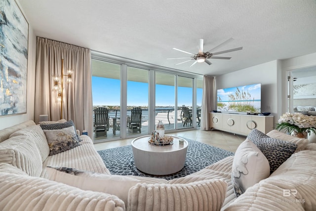 living area with floor to ceiling windows, light tile patterned floors, a ceiling fan, and a healthy amount of sunlight